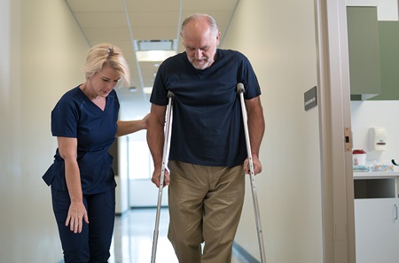 Patient walking with crutches assisted by medical provider